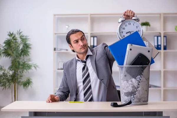 Fired young businessman with recycle bin in time management conc