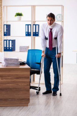 İş yerinde koltuk değnekleriyle yaralı erkek çalışan.