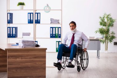 İş yerinde tekerlekli sandalyede oturan boynu yaralı genç bir erkek.