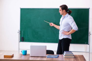 Tahtanın önündeki genç erkek öğretmen.