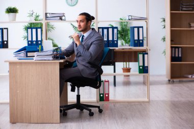 Genç bir erkek çalışan ve ofiste çok fazla iş var.