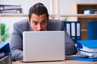 Genç bir erkek çalışan ve ofiste çok fazla iş var.