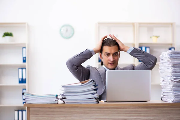 Joven empleado masculino infeliz con el trabajo excesivo — Foto de Stock