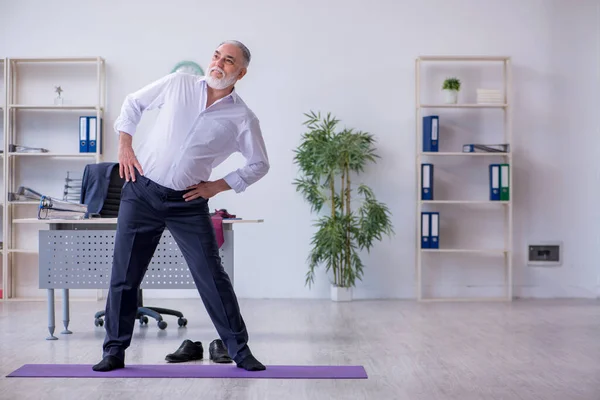 Empleado varón envejecido haciendo ejercicios físicos durante el descanso — Foto de Stock