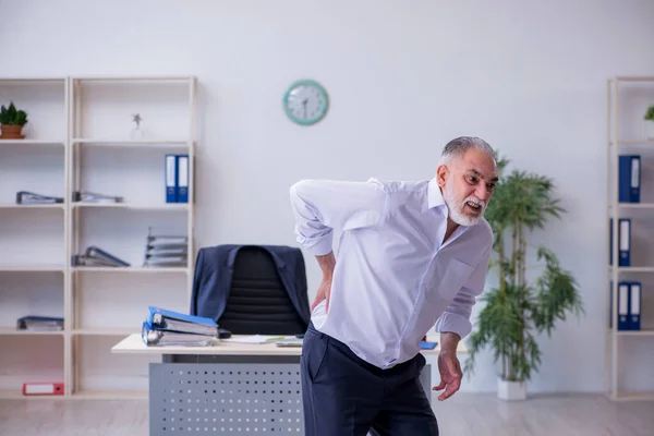 Verouderde mannelijke werknemer doet fysieke oefeningen tijdens de pauze — Stockfoto