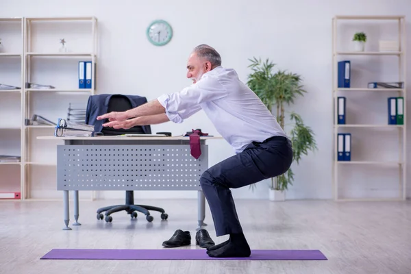 Åldrad manlig anställd som motionerar under pausen — Stockfoto