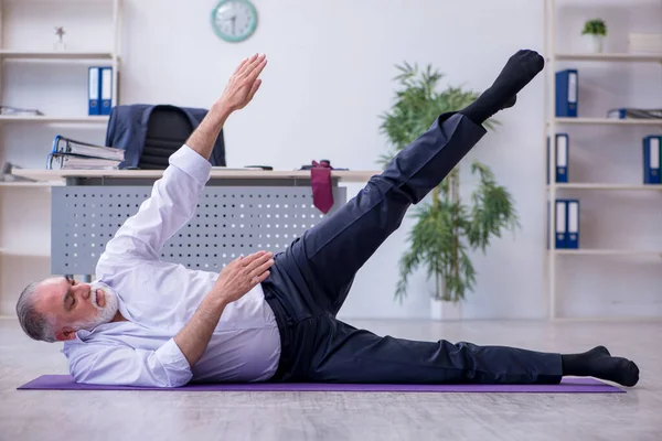 Ältere männliche Mitarbeiter machen in der Pause körperliche Übungen — Stockfoto