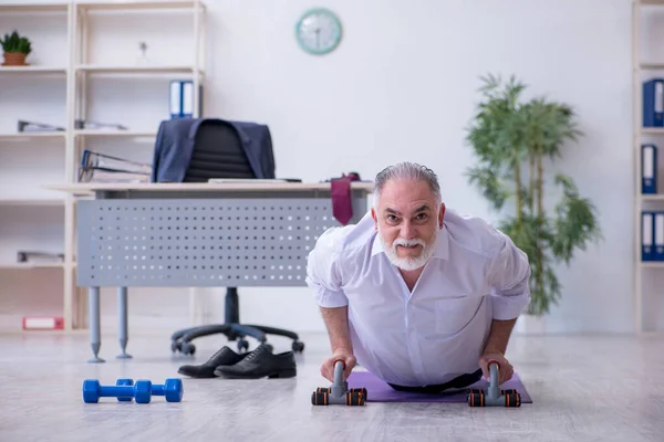 Åldrad manlig anställd som motionerar under pausen — Stockfoto