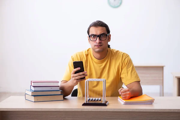 Young male student holding mobile phone during exam preparation — Stock Photo, Image