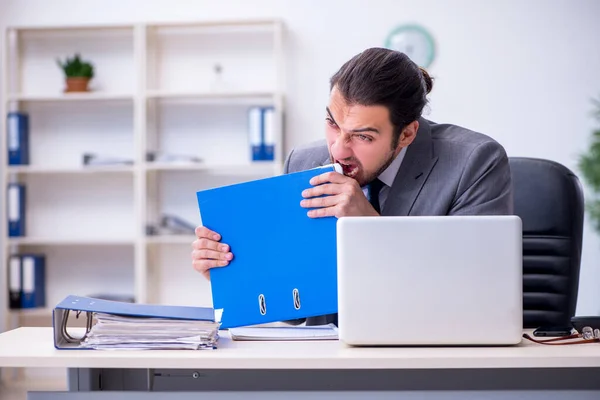 Jovem funcionário masculino infeliz com excesso de trabalho no escritório — Fotografia de Stock