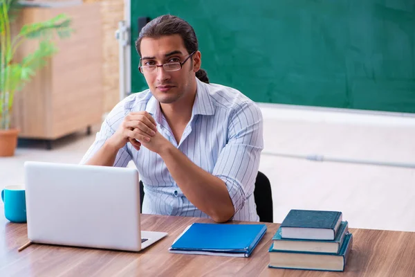 Mladý muž učitel před tabulí — Stock fotografie