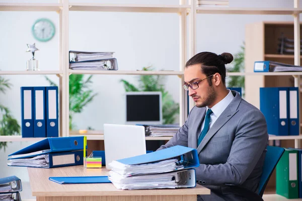 Ung manlig anställd och för mycket arbete på kontoret — Stockfoto