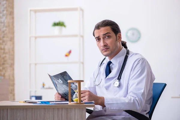 Joven médico masculino en concepto de gestión del tiempo —  Fotos de Stock