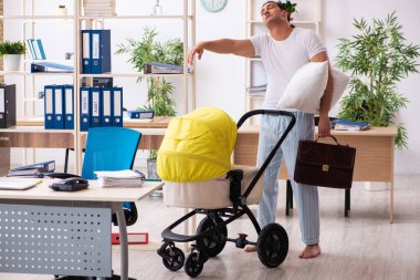 İş yerinde yeni doğan bebeğe bakan genç bir erkek işçi.