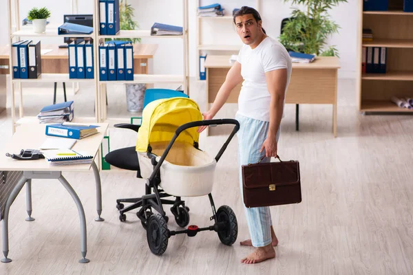 Joven empleado masculino que cuida del recién nacido en el lugar de trabajo — Foto de Stock