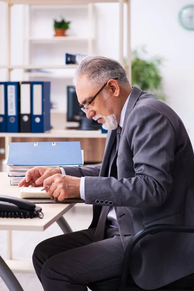 Oude mannelijke werknemer die op kantoor werkt — Stockfoto