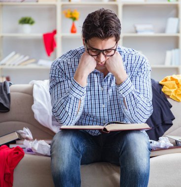 Genç adam dağınık bir odada çalışıyor.