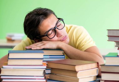 Sınavdan önce okumak için çok fazla kitabı olan öğrenci