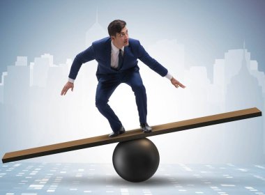 Top ve tahterevalli üzerinde denge kurmaya çalışan bir işadamı