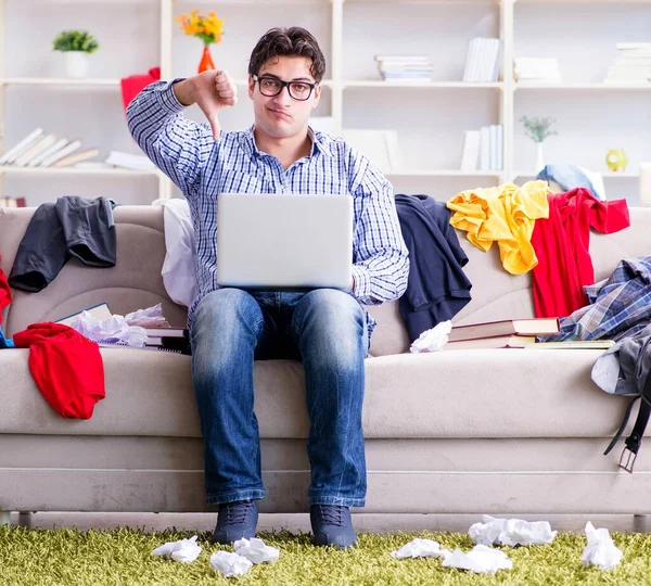 Jeune homme travaillant dans une chambre désordonnée — Photo