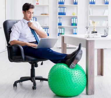 Genç işadamı iş yerinde spor yapıyor.