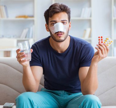 Genç adam estetik cerrahi burnundan sonra evde iyileşiyor.