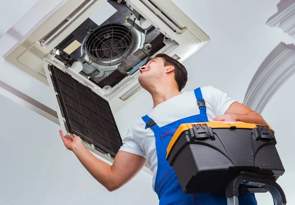 Worker repairing ceiling air conditioning unit — Stock Photo, Image