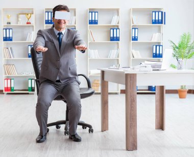 Ofiste egzersiz yapan işadamı VR gözlüğü takıyor.