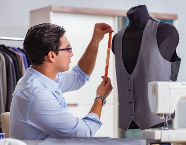 Genç terzi yeni elbiseler üzerinde çalışıyor.