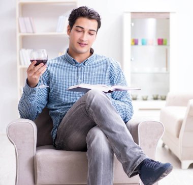 Genç adam evde şarap içiyor.