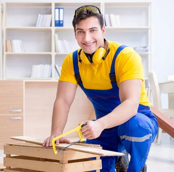 Repairman carpenter working sawing a wooden board with a hand sa — Stock Photo, Image