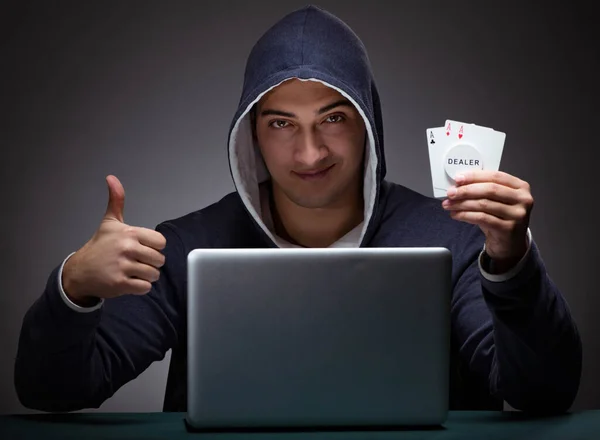 Junger Mann mit Kapuzenpullover sitzt vor einem Laptop — Stockfoto