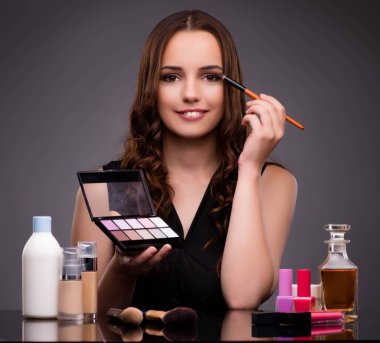 Kadının koyu arka plan üzerinde makyaj yapması