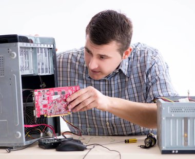 Genç teknisyen atölyede bilgisayar tamir ediyor.