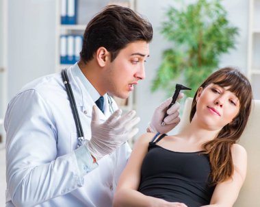 Doktor muayene sırasında hastaların kulaklarını kontrol ediyor.