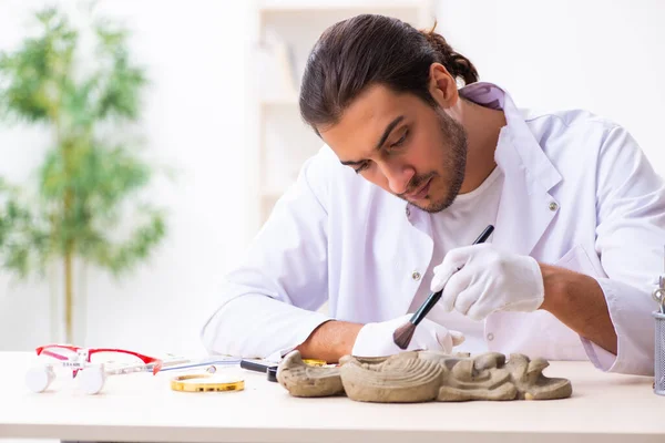 Junger männlicher Archäologe untersucht antike afrikanische Steinmetzarbeit — Stockfoto