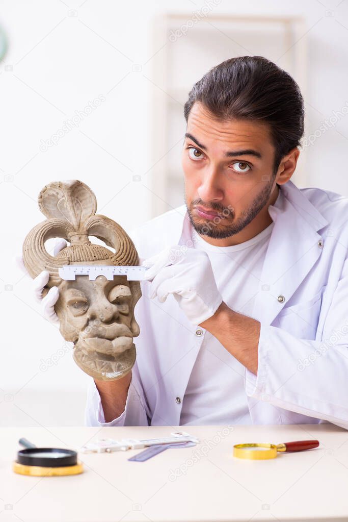 Young male archaeologist studying ancient african stonemask