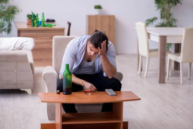 Genç erkek alkolik evde viski içiyor.