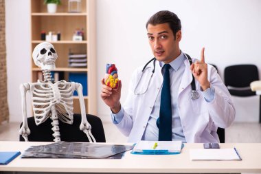Genç erkek doktor kardiyolog ve Clini 'deki iskelet hastası.