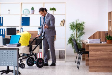 İş yerinde yeni doğan bebeğe bakan genç bir erkek işçi.