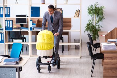 İş yerinde yeni doğan bebeğe bakan genç bir erkek işçi.