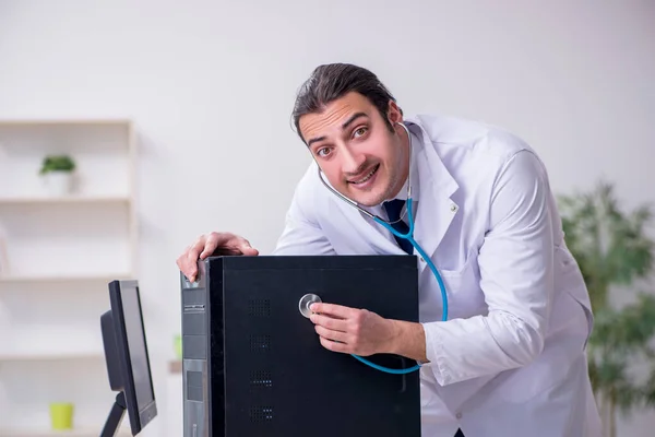 Jeune médecin masculin avec stéthoscope réparer ordinateur — Photo