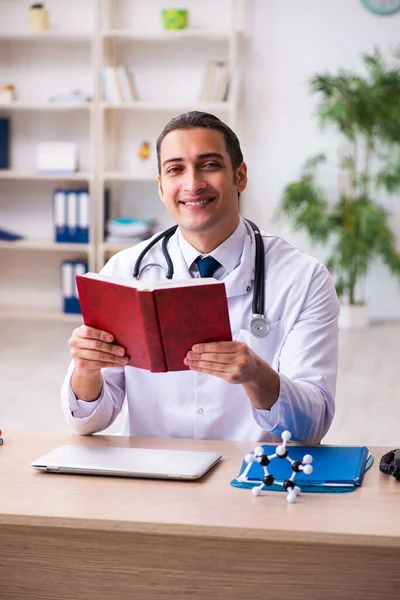 Ung manlig student läkare läsa bok på kliniken — Stockfoto