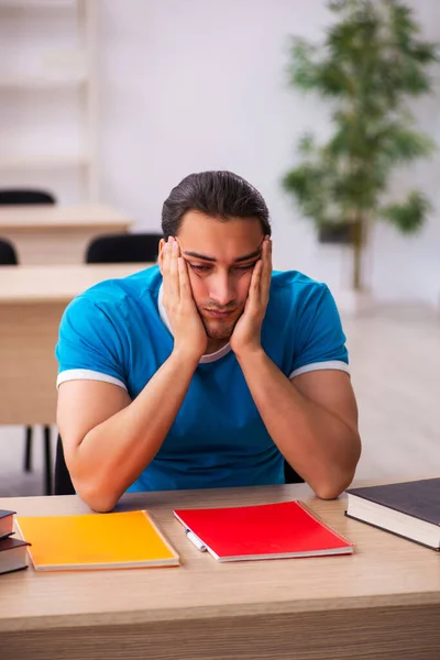 Uitgeputte mannelijke student bereidt zich voor op de examens in de klas — Stockfoto