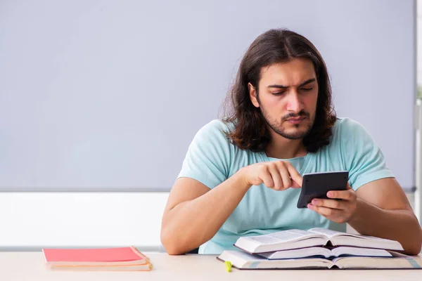 Ung manlig student förbereder sig för tentor i klassrummet — Stockfoto