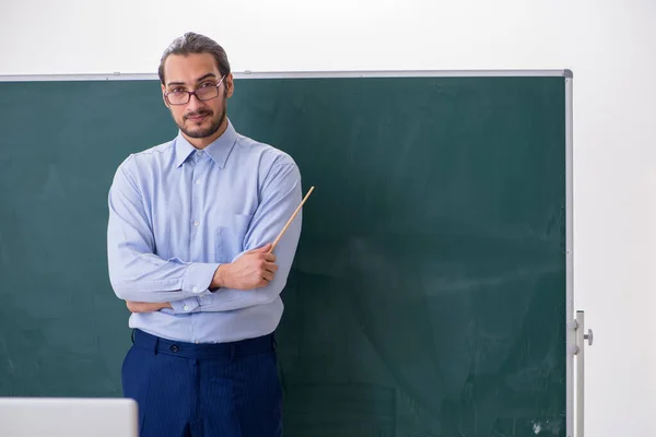 Jovem professor na sala de aula em frente ao quadro verde — Fotografia de Stock