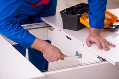 Genç erkek müteahhit içeride masa onarıyor.