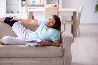 Genç bacak yaralı öğrenci evde çalışıyor.