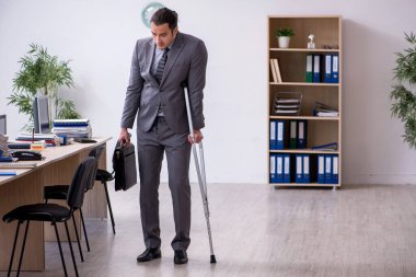 Ofiste çalışan genç bacağı yaralı bir erkek işçi.