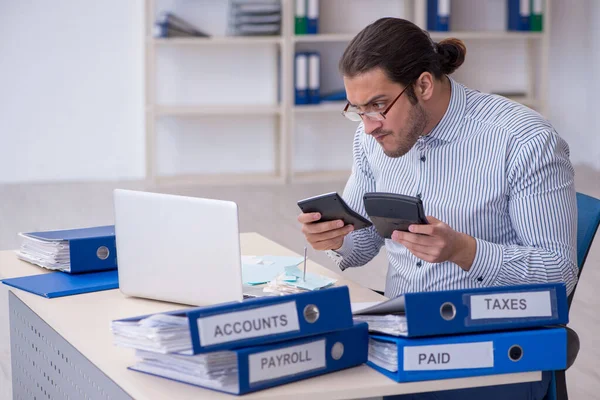 Joven contable masculino calculando los pagos de impuestos en la oficina —  Fotos de Stock